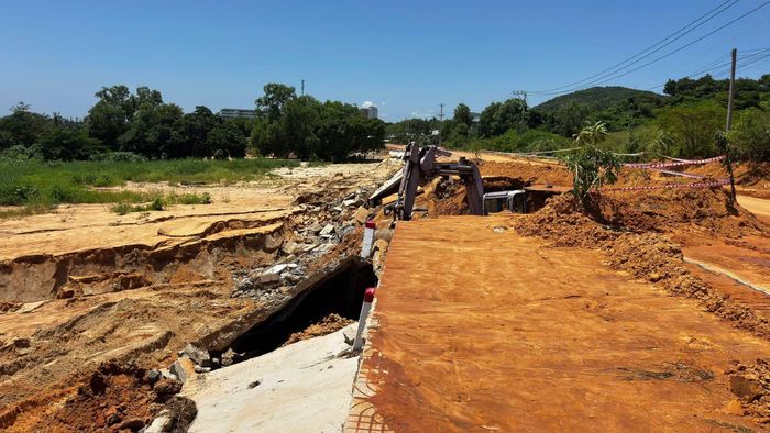 Máy xúc đang cào dọn lớp cát đỏ, khắc phục hậu quả.