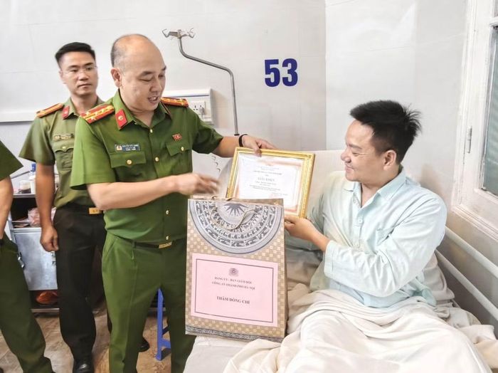 Đại tá Nguyễn Đức Long trao quà và Giấy khen của Giám đốc Công an thành phố tặng Trung tá Hoàng Ngọc Tuấn.
