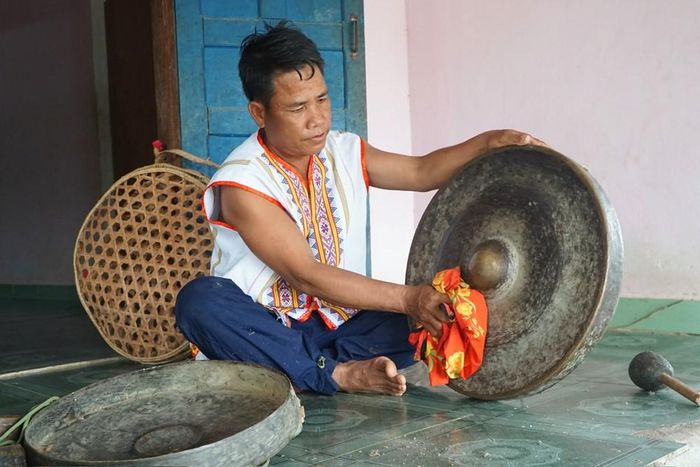 Ông A Ngốc cẩn thận lau chùi bộ cồng chiêng hơn 100 năm tuổi được gia đình gìn giữ qua nhiều thế hệ
