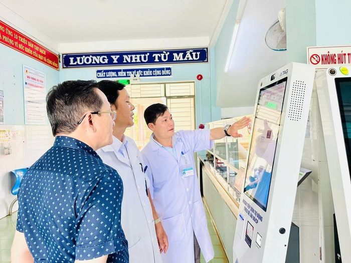 Cán bộ y tế hướng dẫn vận hành ki-ốt thông minh tại Cơ sở y tế. Ảnh: Quang Thái- TTXVN