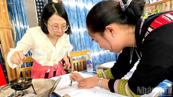 Hướng dẫn du khách cách sử dụng bút vẽ sáp ong. (Ảnh: NGỌC LIÊN)