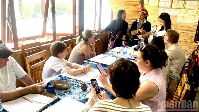 Du khách nước ngoài tìm hiểu kỹ thuật vẽ hoa văn bằng sáp ong. (Ảnh: NGỌC LIÊN)