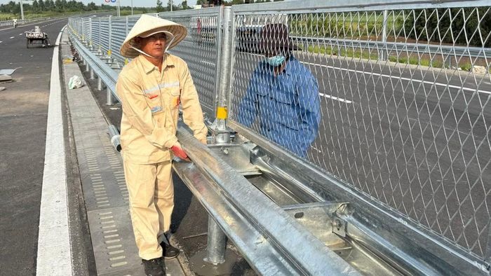 Công nhân kiểm tra, hoàn thiện lưới gắn lan can trên cao tốc trước giờ thông xe. (Ảnh: QUÝ HIỀN)