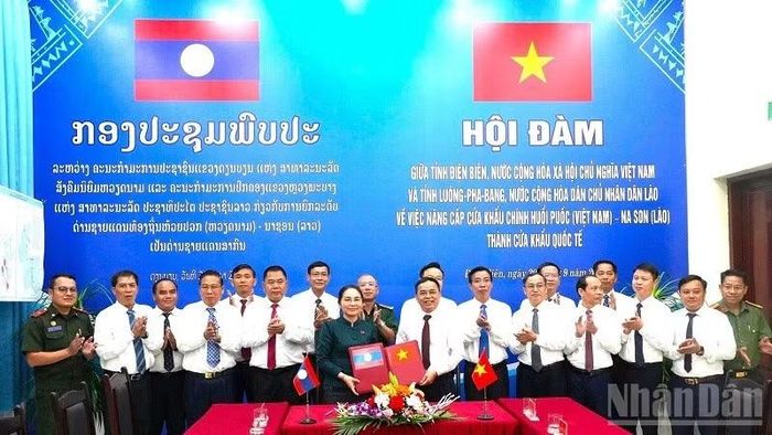 Hai đồng chí Trưởng đoàn trao biên bản hội đàm ký kết về việc thống nhất báo cáo cấp có thẩm quyền nâng cấp cặp cửa khẩu chính Huổi Puốc (Việt Nam)-Na Son (Lào) thành cửa khẩu quốc tế. (Ảnh: LÊ LAN)