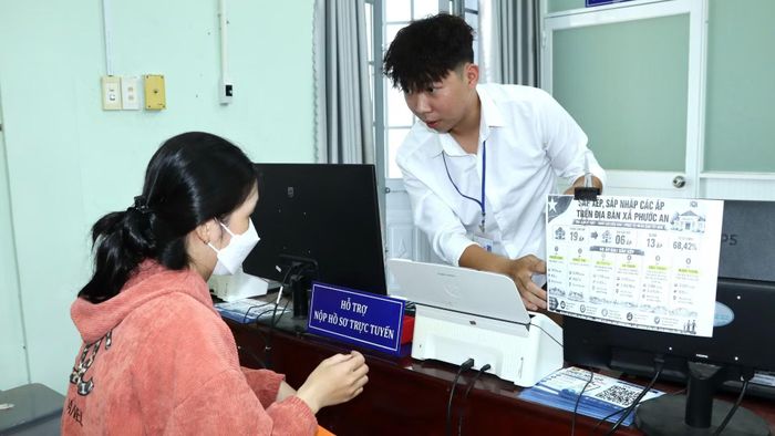Cán bộ Trung tâm phục vụ hành chính công xã Phước An hỗ trợ người dân nộp hồ sơ trực tuyến. (Ảnh: THIÊN VƯƠNG)