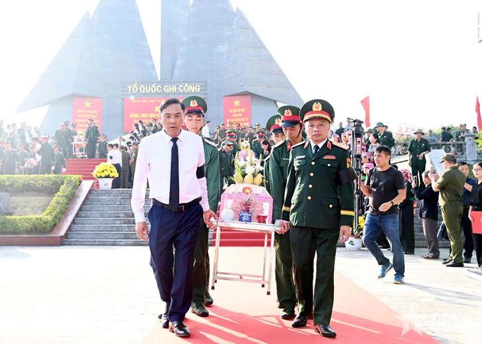 Các đại biểu tham gia di chuyển hài cốt liệt sĩ lên xe quân sự, đưa đến nghĩa trang tổ chức an táng.