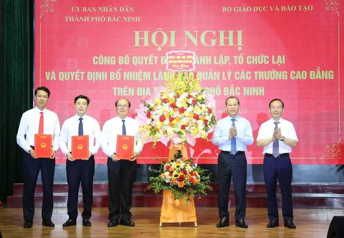 Ông Mai Sơn, Phó Chủ tịch Thường trực UBND TP Bắc Ninh và Phó Trưởng Đoàn Đại biểu Quốc hội thành phố Trần Văn Tuấn tặng hoa chúc mừng và trao các Quyết định của Bộ GD&ĐT về thành lập, tổ chức lại các trường.