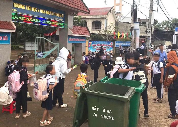 Học sinh Trường Tiểu học và THCS Nguyễn Trường Tộ (phân hiệu 2) ăn sáng trước cổng trường có 2 thùng rác lớn.