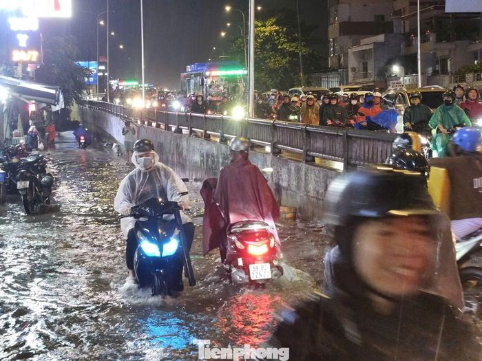 Tại đường Nguyễn Văn Quá, nước dâng cao sau mưa lớn khiến người dân chật vật di chuyển, nhiều phương tiện phải giảm tốc để vượt qua đoạn ngập.