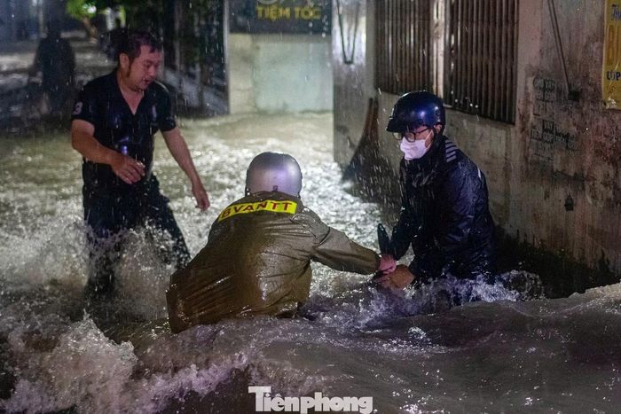 Lực lượng chức năng hỗ trợ người dân bị té ngã khi di chuyển qua đoạn ngập sâu trên đường Lý Tế Xuyên, phường Hiệp Bình, TPHCM.