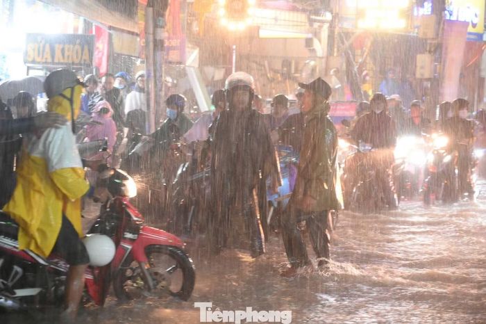  Dòng xe cộ di chuyển chậm qua vùng ngập. Nhiều người phải tấp vội lên vỉa hè, chờ nước rút rồi mới tiếp tục hành trình. 
