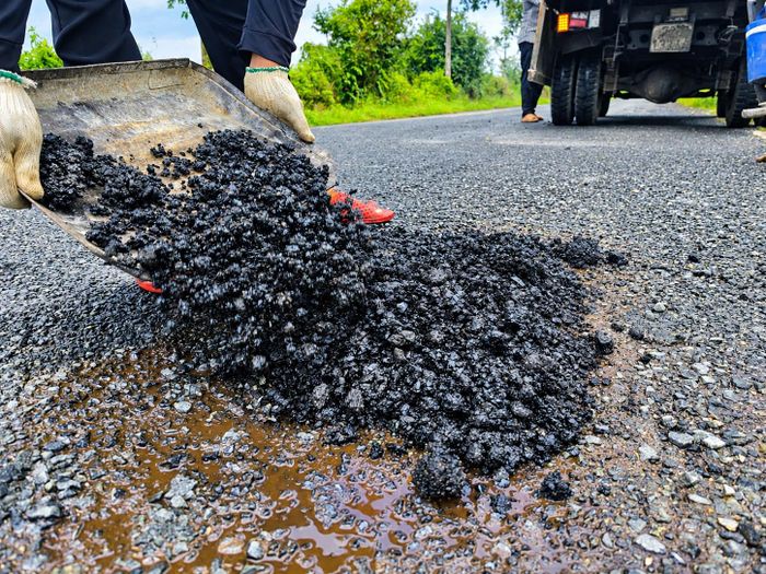 Tại một số vị trí xuất hiện ổ gà, công nhân đã đưa bê tông nhựa nóng vào các điểm hư hỏng, sau đó tiến hành gạt và lu lèn. Ảnh: Ký Long