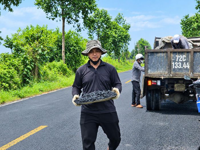 Công nhân đưa bê tông nhựa nóng đến vá ổ gà. Ảnh: Ký Long