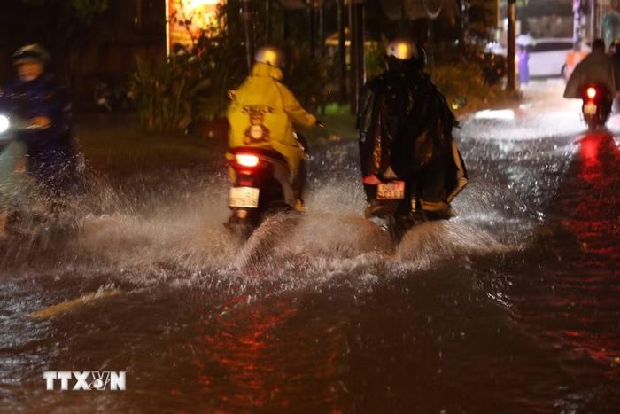 Người dân Thành phố Hồ Chí Minh di chuyển trong mưa và ngập tối 30/9 trên đường Bình Quới, phường Bình Quới. (Ảnh: Hồng Đạt/TTXVN)