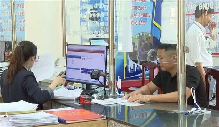 Cán bộ Trung tâm Phục vụ hành chính công xã Thuận Lợi tiếp nhận, xử lý hồ sơ cho người dân, với sự hỗ trợ của các thiết bị công nghệ tại quầy giao dịch.