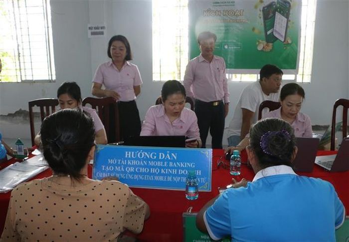 Tư vấn trực tiếp, giúp các hộ buôn bán nhỏ lẻ mở tài khoản thanh toán và tạo mã QR để niêm yết tại cửa hàng. Ảnh: Duy Khương – TTXVN