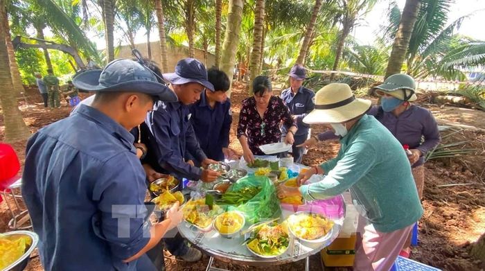 Người dân xã Tân Thành (Đồng Tháp) hỗ trợ đồ ăn, nước uống cho Đội K91 trong quá trình tìm kiếm, khai quật hài cốt liệt sĩ. Ảnh: TTXVN phát