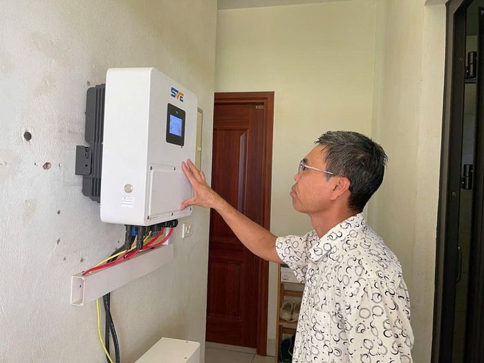 Anh Phạm Văn Hoàng Thuỷ kiểm tra thiết bị biến tần hybrid của hệ thống điện mặt trời mái nhà của gia đình. Ảnh: Anh Nguyễn/Bnews/vnanet.vn