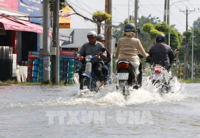 Người dân di chuyển khó khăn trên đoạn đường bị ngập do triều cường ở phường Sa Đéc (Đồng Tháp). Ảnh: Hồng Thái - TTXVN