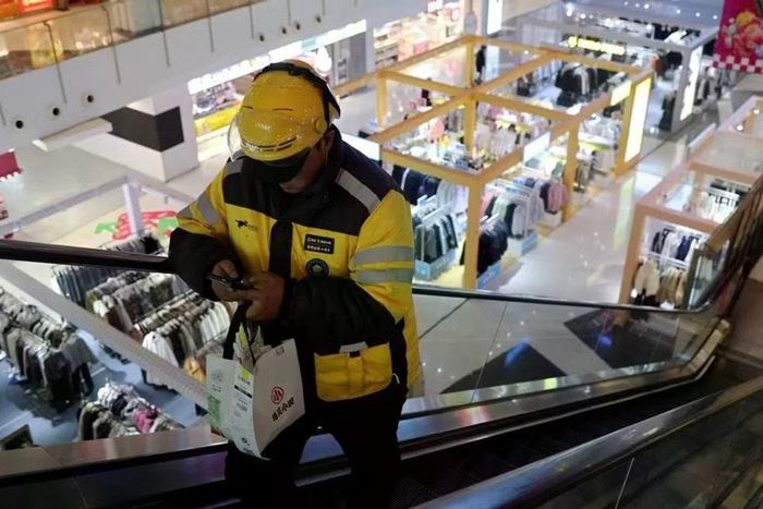 Một nhân viên giao hàng của Meituan nhận đơn thức ăn tại một trung tâm thương mại ở Bắc Kinh, Trung Quốc