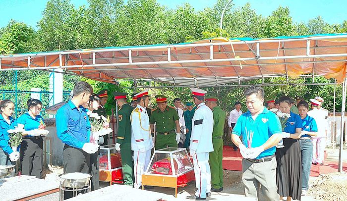 Thực hiện nghi thức an táng hài cốt liệt sĩ tại nghĩa trang xã Quế Phước. Ảnh: MINH THÔNG