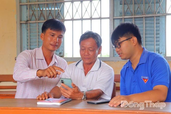 Đảng viên trẻ, Chi bộ ấp Mỹ Long 4, xã Mỹ Hiệp hướng dẫn ông Trần Quốc Khải sử dụng Sổ tay đảng viên điện tử, chủ động tiếp cận tài liệu trên nền tảng số.