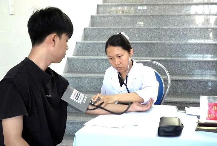 Nhân viên y tế đo huyết áp cho thanh niên.