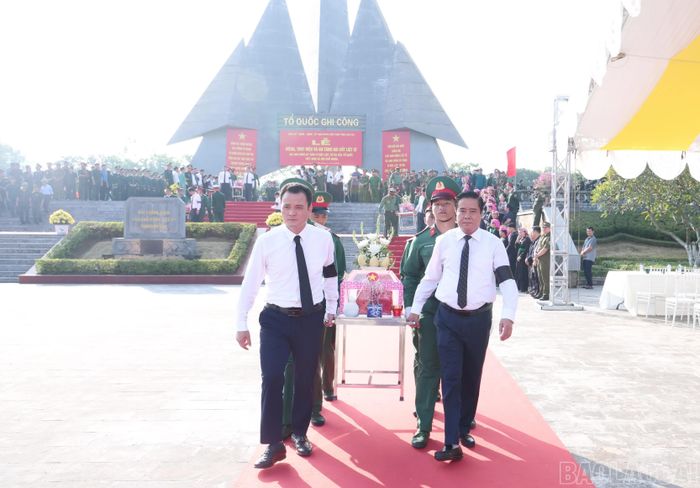 Các đại biểu thực hiện nghi thức di quan, đưa hài cốt các liệt sĩ về an táng tại nghĩa trang liệt sĩ.