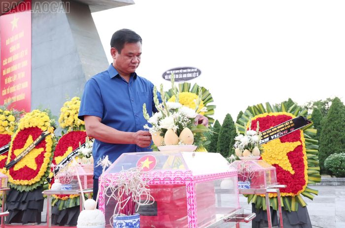  Trong số 71 hài cốt liệt sĩ được an táng lần này, có 2 liệt sĩ đã xác định được danh tính ﻿Trong ảnh: Ông Lý Tiến Nam bên hài cốt bố mình là liệt sĩ Lý A Tờ. 