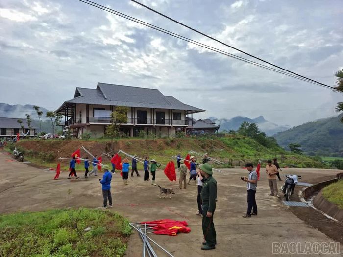 Các tổ chức đoàn thể, chính trị xã hội và Nhân dân cùng nhau lắp đặt đường cờ tại Khu tái định cư Làng Nủ.
