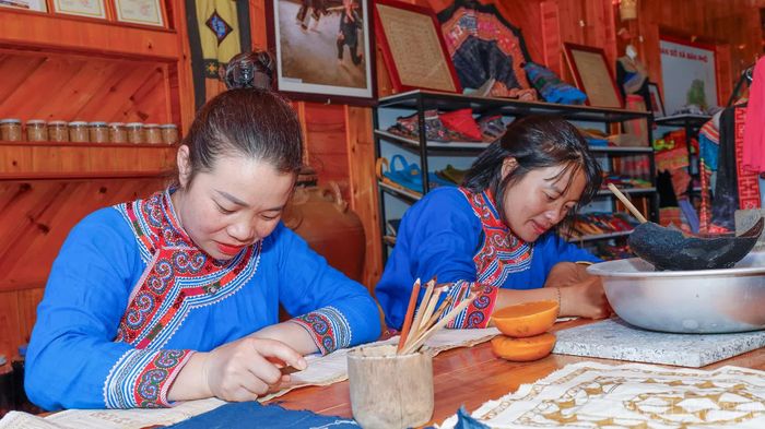  Chị Sùng Thị Xoa ﻿và chị Ly Thị Rua vẽ sáp ong bằng dụng cụ truyền thống, tạo nên những đường nét hoa văn tinh tế trên tấm vải lanh dệt thủ công. 