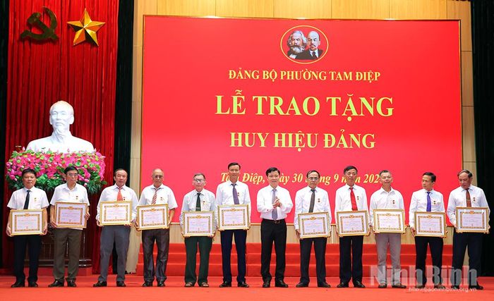 Đồng chí Đặng Đức Tân, Tỉnh uỷ viên, Bí thư Đảng uỷ, Chủ tịch HĐND phường Tam Điệp trao Huy hiệu Đảng cho các đảng viên. Ảnh: Anh Tuấn