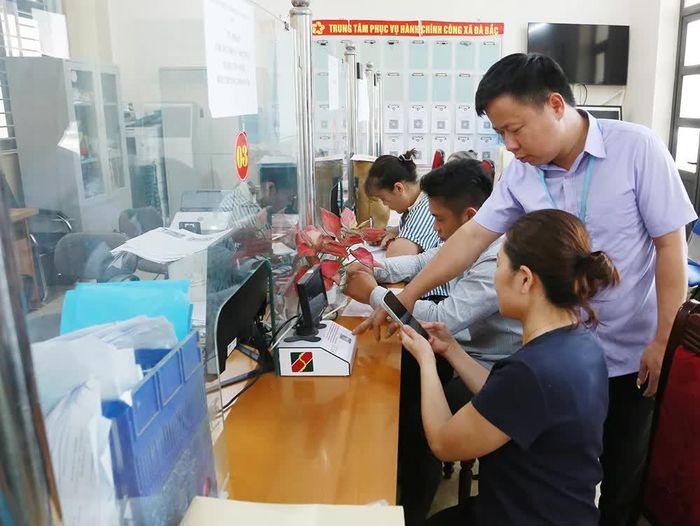 Cán bộ Trung tâm Phục vụ hành chính công xã Đà Bắc hỗ trợ người dân sử dụng mã QR trong thực hiện thủ tục.
