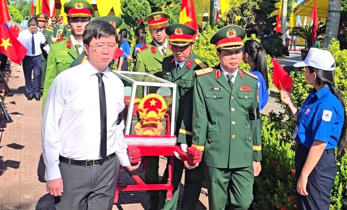 Thiếu tướng Lê Văn Trung, Phó chính ủy Quân khu 4 (bên phải) và Chủ tịch UBND tỉnh Quảng Trị Bùi Hoàng Phương (bên trái) thực hiện nghi thức di chuyển hài cốt liệt sĩ đến nơi an táng.
