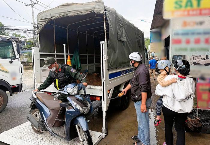 Cán bộ Công an sử dụng xe ô tô chở phương tiện cho người dân qua đoạn đường bị ngập.