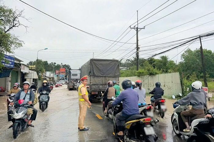 CSGT hướng dẫn người dân di chuyển qua đoạn đường bị ngập nước.