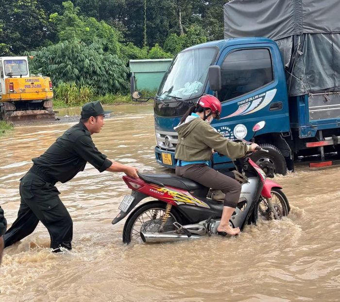 Người dân đi làm buổi sáng qua đoạn đường ngập nước xe chết máy, cán bộ Công an hỗ trợ đẩy xe.