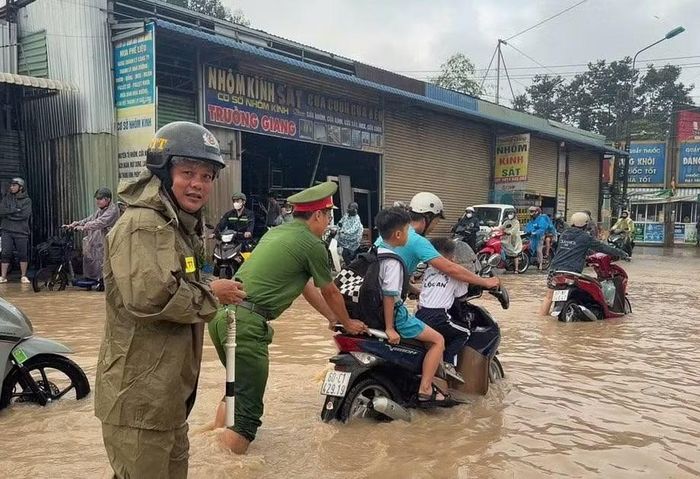 Cán bộ Công an phường Long Thành hỗ trợ đẩy xe cho người dân chở con đi học qua đoạn đường bị ngập.