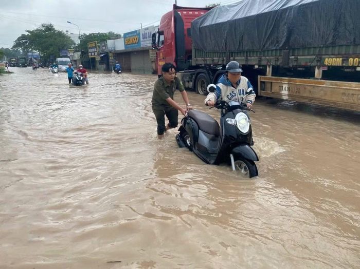 Lực lượng ANTT cơ sở hỗ trợ đẩy xe máy cho người dân bị nước ngập.