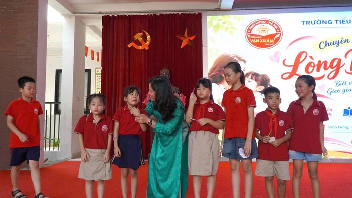 Trên sân khấu dưới mái trường Vạn Xuân, cô Hạnh đang vỗ về từng em nhỏ khi các em xúc động nghĩ về bài học biết ơn gia đình và thầy cô.