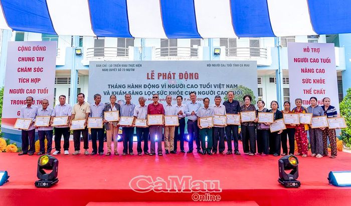 Ông Nguyễn Văn Khởi, Phó Chủ tịch Uỷ ban MTTQ Việt Nam tỉnh Cà Mau (thứ 11 từ phải sang) và ông Phạm Anh Tuấn, Chủ tịch Hội Người cao tuổi tỉnh Cà Mau (thứ 11 từ trái sang), trao thiếp mừng thọ