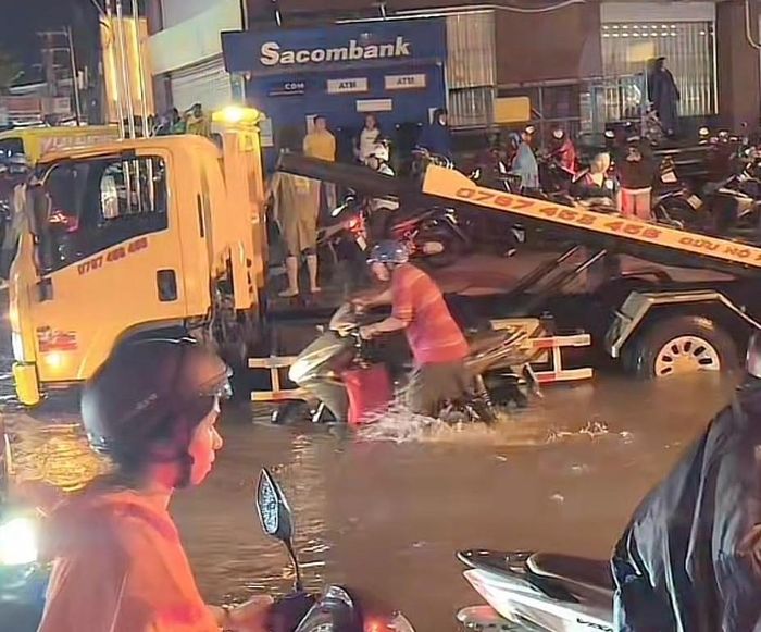 Đến tối 30/9, nhiều người đi xe máy vẫn bì bõm trên đường. Xe cứu hộ cũng tranh thủ đến trợ giúp các ô tô bị chết máy vì nước ngập. (Ảnh: B.L)