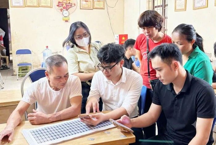 Các ngành chức năng hướng dẫn hộ kinh doanh chợ đầu mối Minh Khai (phường Xuân Phương) kê khai thông tin và kích hoạt mã truy xuất nguồn gốc. Ảnh: Nguyễn Tùng