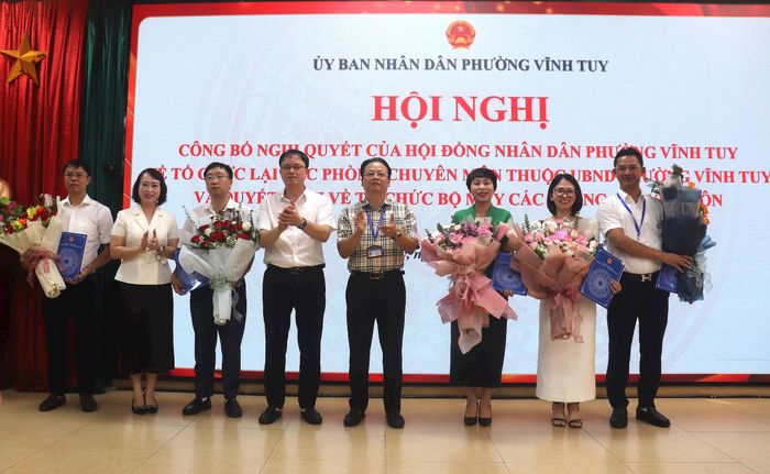 Bí thư Đảng ủy, Chủ tịch HĐND phường Vĩnh Tuy Nguyễn Quang Trung và các đồng chí Thường trực Đảng ủy phường trao quyết định, tặng hoa chúc mừng lãnh đạo 5 phòng chuyên môn. Ảnh: Linh Chi
