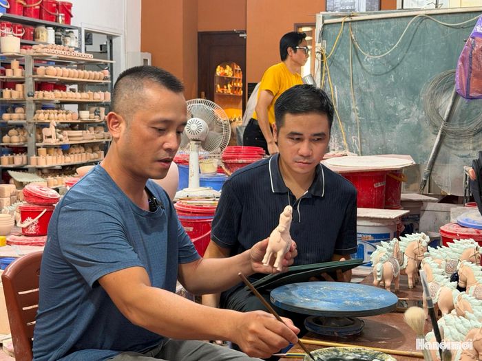 Nghệ nhân Trần Anh Tú hướng dẫn người thợ gốm phối màu sản phẩm mới (ảnh: PV).