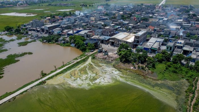 Một góc thôn Bình Yên nằm sát kênh mương bị bao phủ bởi màu nước xả thải đổi màu bất thường và bùn tích tụ lâu ngày do hoạt động làng nghề.