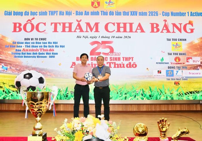 Ông Đỗ Trần Quân - Phó trưởng Ban Biên tập An ninh Thủ đô, đại diện Ban tổ chức giải tiếp nhận bóng thi đấu từ ông Mai Thế Hưng - Giám đốc đối ngoại Công ty cổ phẩn tập đoàn Động Lực, đơn vị tài trợ giải