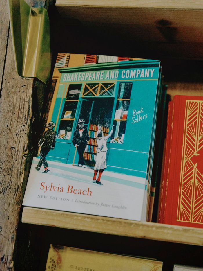 Ảnh trái: Sylvia Whitman, con gái người sáng lập hiệu sách và hiện là người điều hành cửa hiệu. Bà được đặt tên theo Sylvia Beach, người đã sáng lập nên hiệu sách Shakespeare and Company đời đầu. Ảnh phải: Sách về lịch sử của cửa hiệu đời đầu, do chính người sáng lập soạn thảo. Ảnh: Economist.