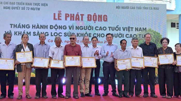 Phó Chủ tịch Ủy ban Mặt trận Tổ quốc Việt Nam tỉnh Cà Mau Nguyễn Văn Khởi (thứ 6 từ phải qua) tặng quà mừng thọ người cao tuổi tại lễ phát động. (Ảnh: HOÀN THÀNH)