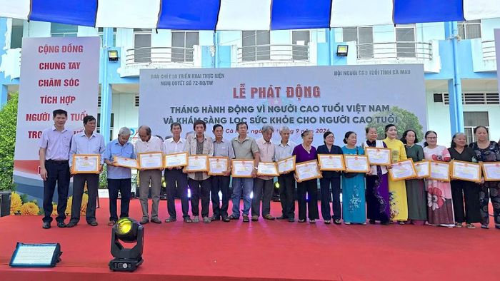 Đại diện lãnh đạo Ủy ban Mặt trận Tổ quốc Việt Nam tỉnh Cà Mau và Sở Y tế Cà Mau vinh danh người cao tuổi có nhiều cống hiến cho địa phương tại lễ phát động. (ảnh HOÀN THÀNH)